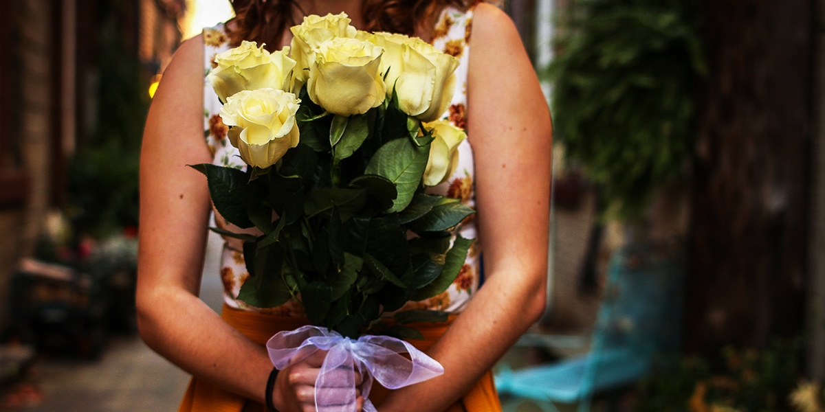 woman holding a bouquet of yellow roses.