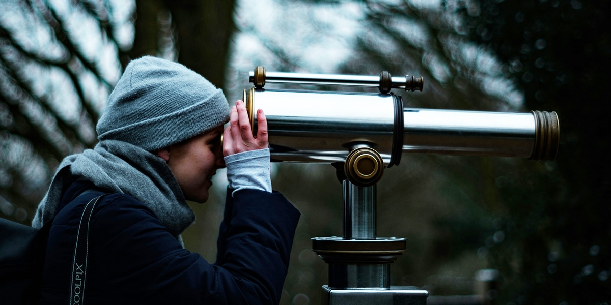 Woman looking beyond through telescope
