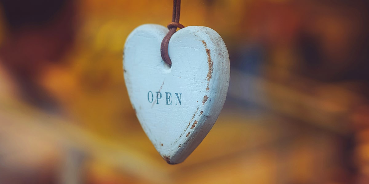 a wooden white painted heart with the words open on it.