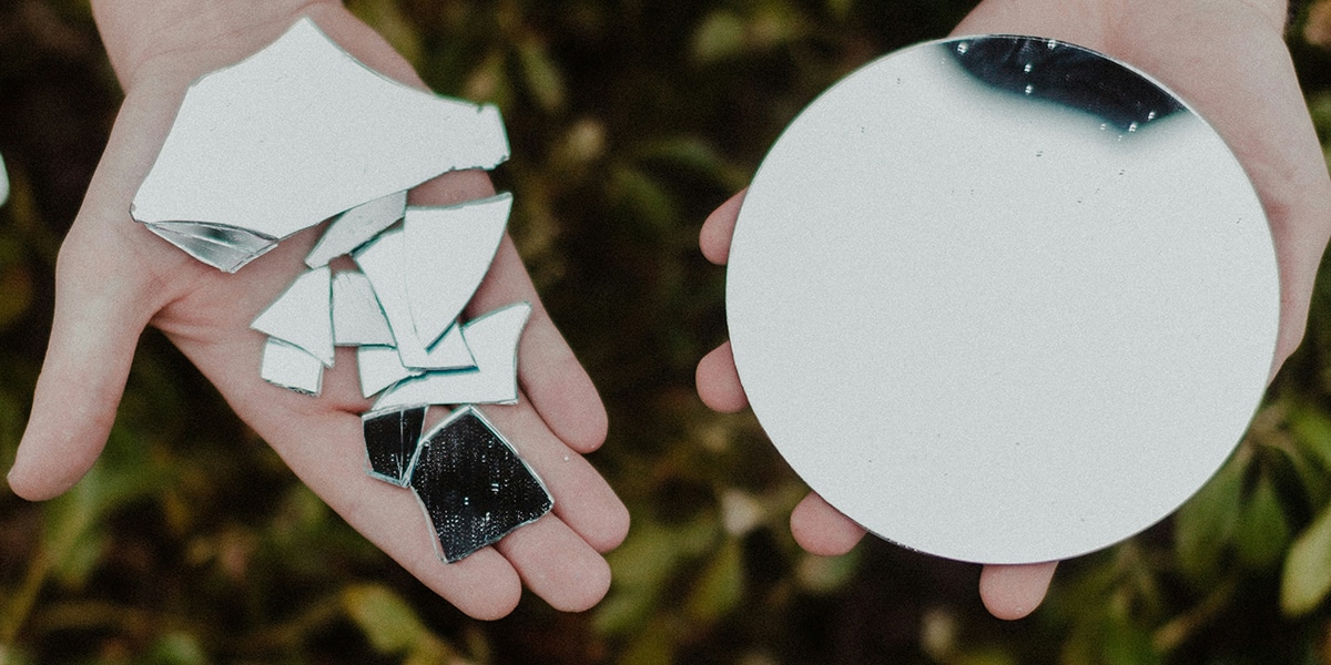 hands holding pieces of broken plate