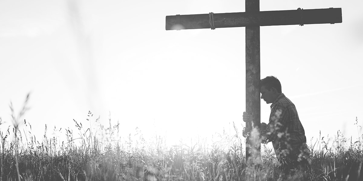 man kneeling before a cross