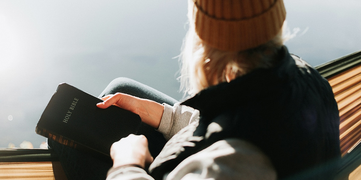 teen female praying while holding a Bible
