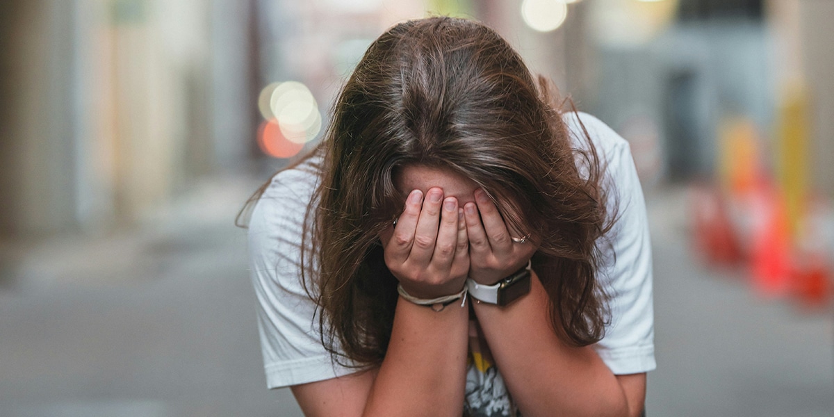 woman covering her face with her hands while crying