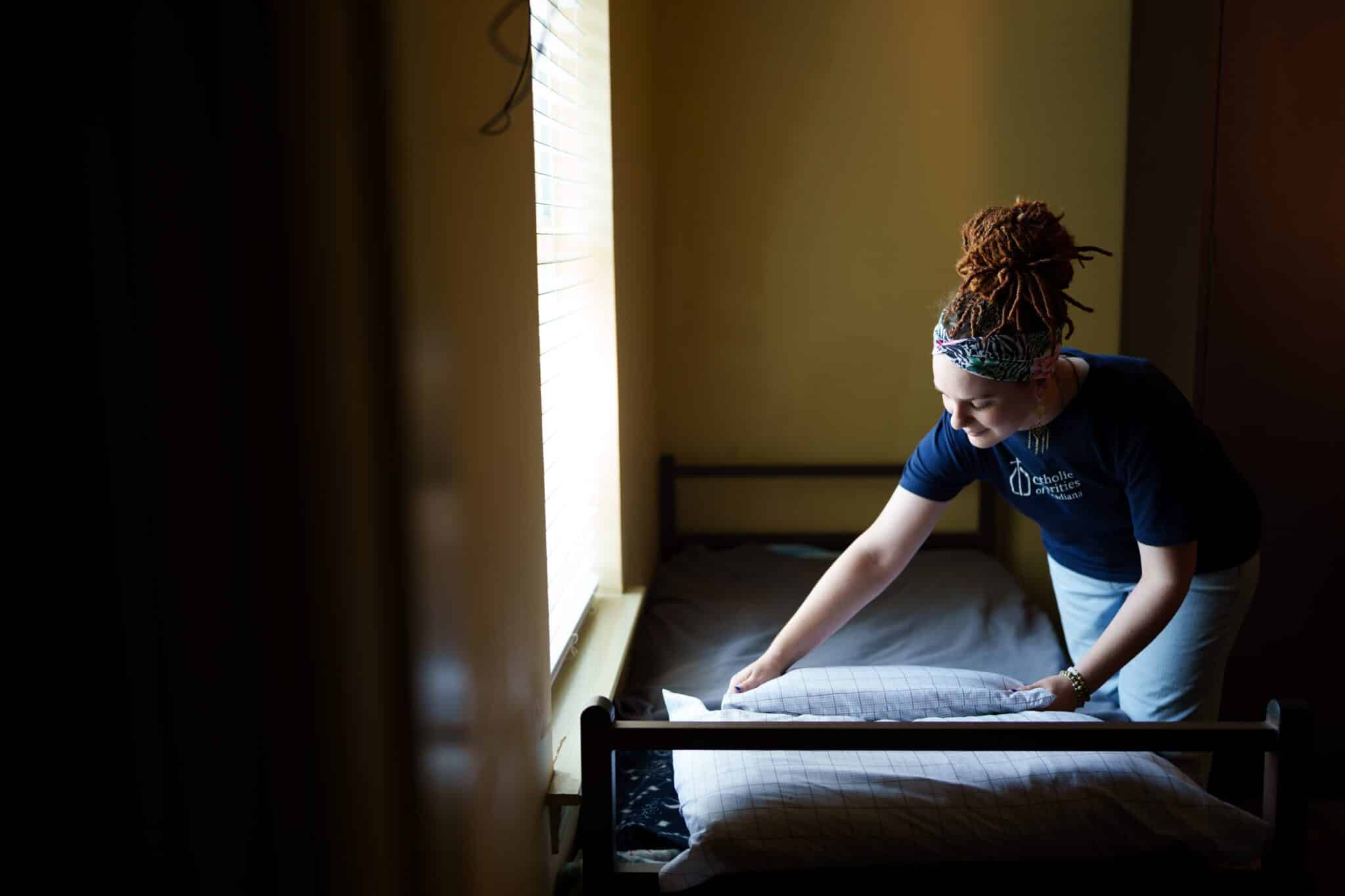 A case worker with Catholic Charities of Acadiana is pictured in a file photo preparing a bed at St. Joseph Shelter, an emergency shelter that cares for 87 individuals experiencing homelessness in and around Lafayette, La.