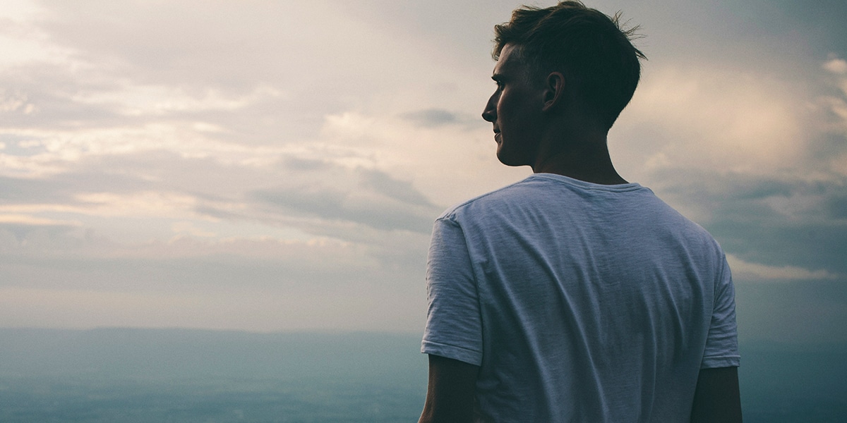 man standing on the mountain and looking into the distance