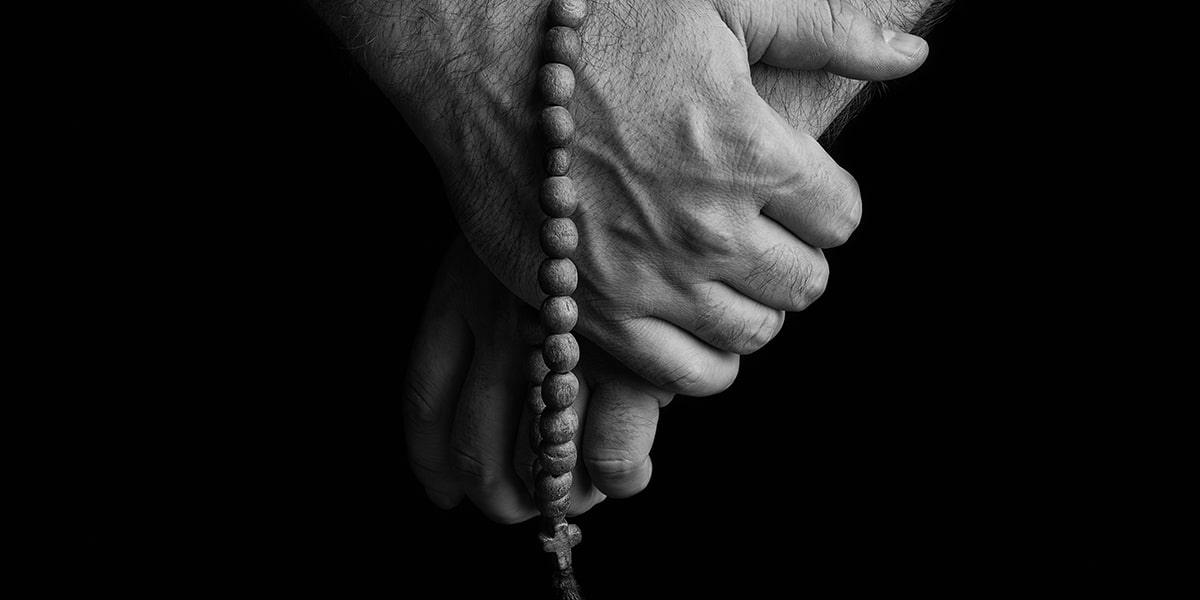 hands folded in prayer with a rosary.