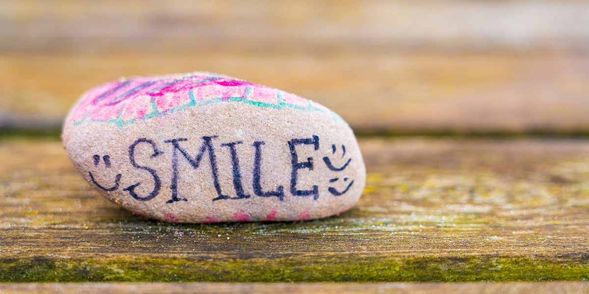 A rock with the word smile painted on it.