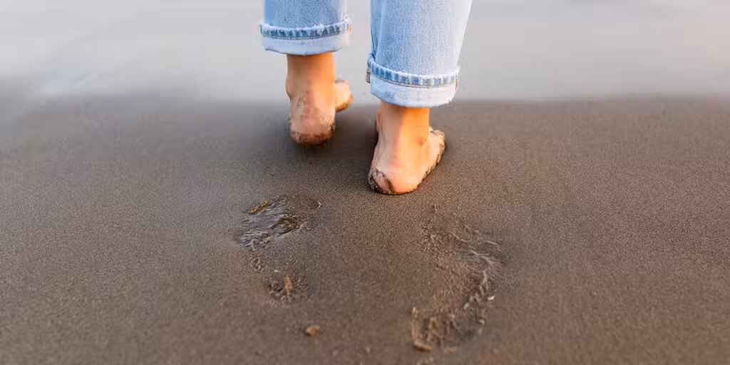 person making footprints in the sand