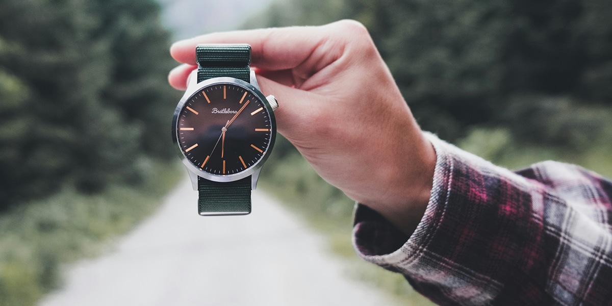 Hand holding a watch showing the time.