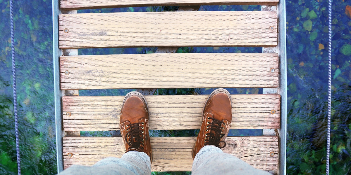 feet walking across a hanging bridge.