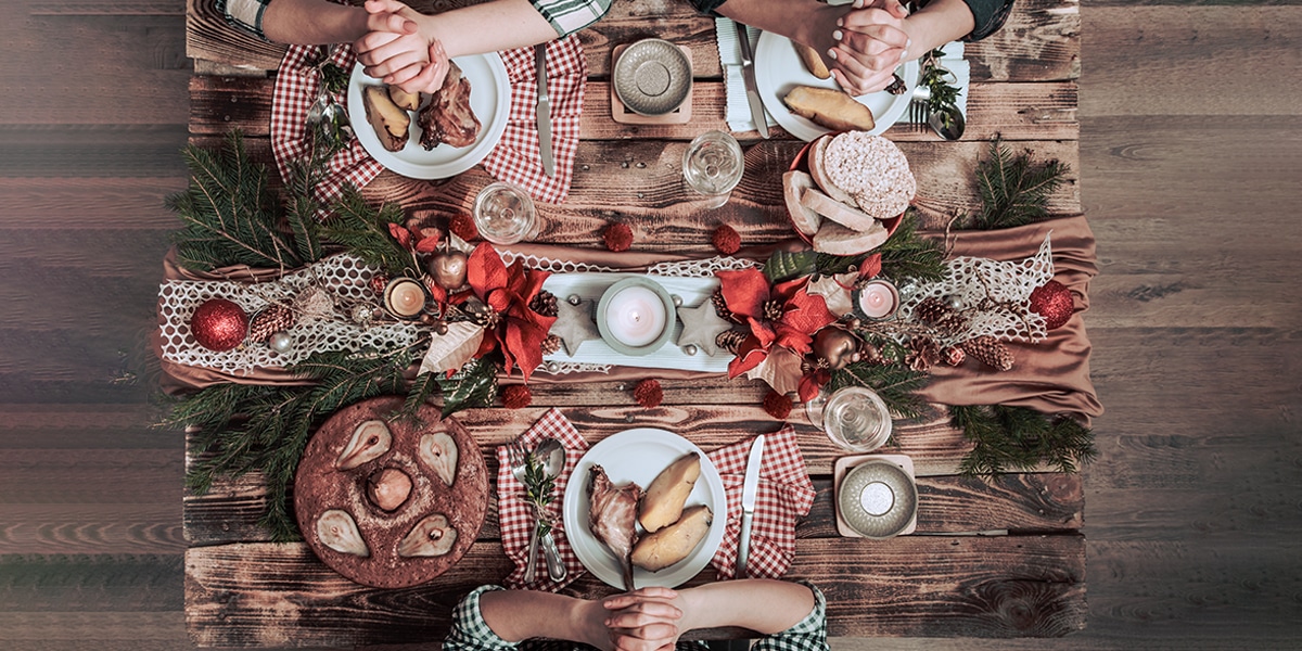 hands folded in prayer around a dinner table