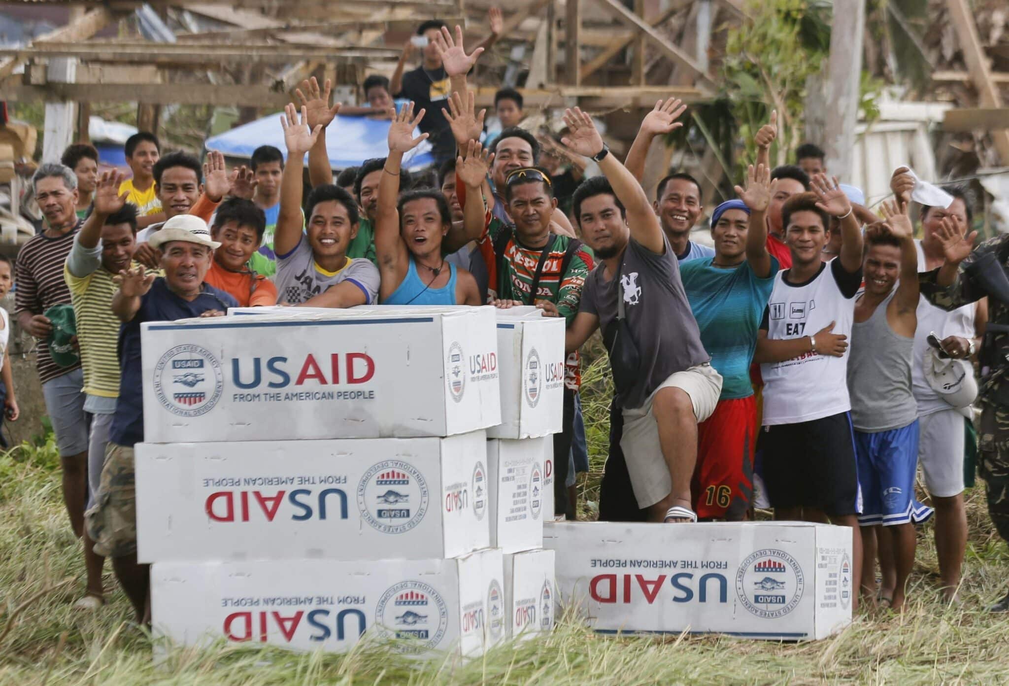 Filipinos are seen in a 2013 photo showing their gratitude and waving to the crew of a U.S. Navy aircraft after receiving aid from U.S. Agency for International Development.