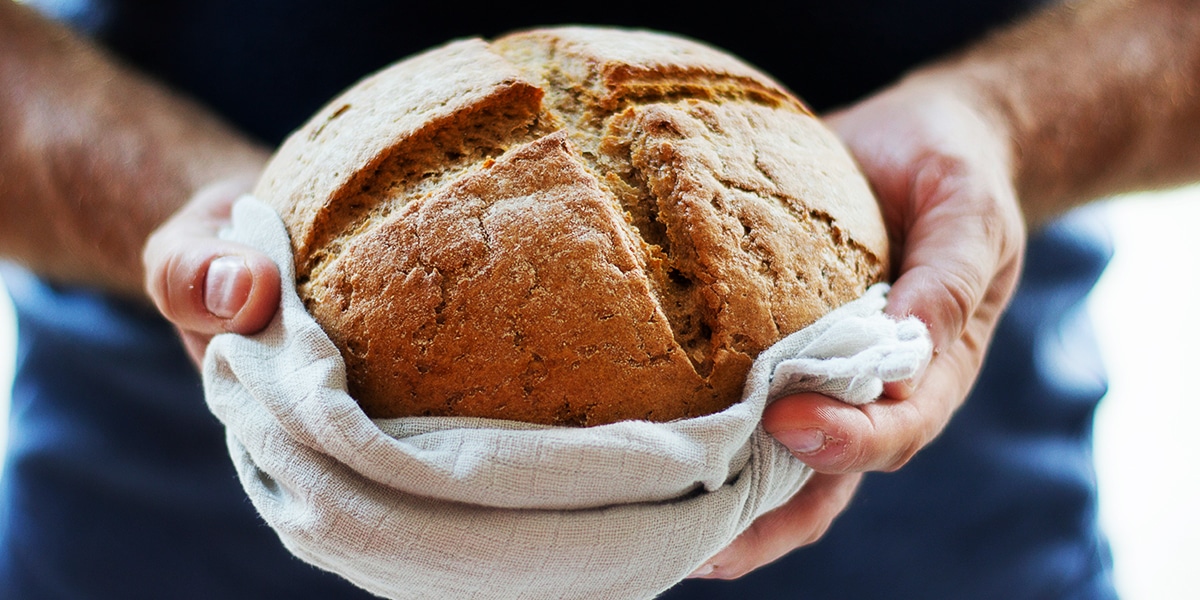 hands holding a fresh loaf of bread
