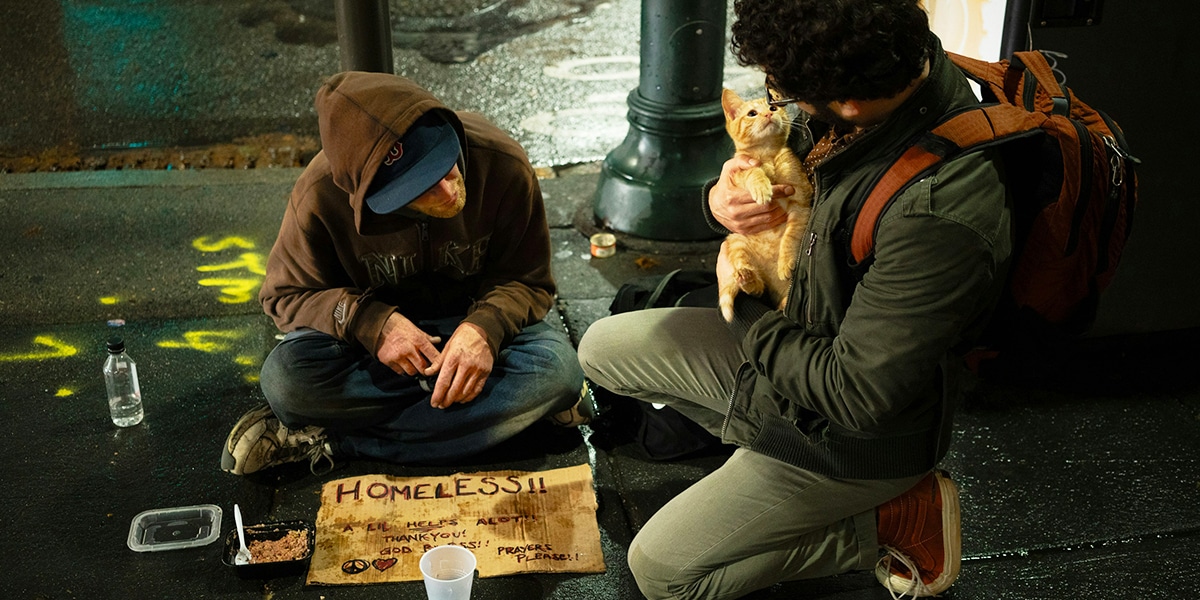 A man visiting a homeless person and having a conversation.