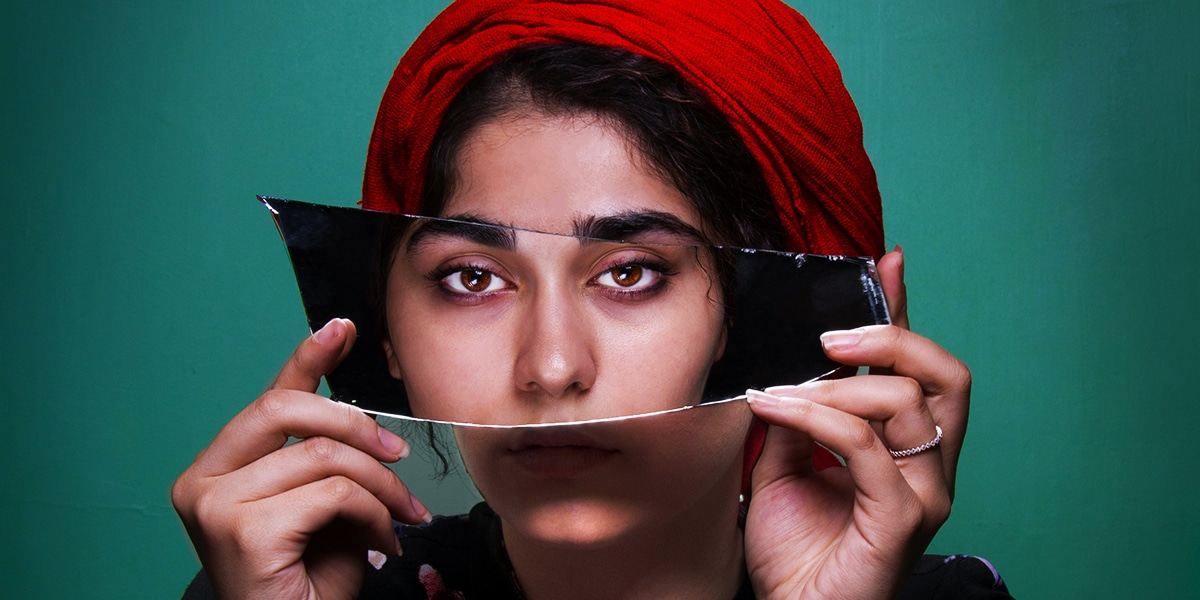 woman showing her face in a broken mirror.