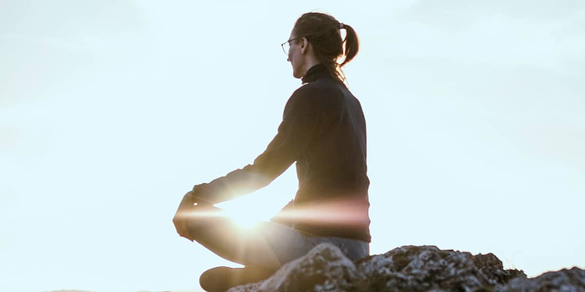 person sitting peacefully on a rock while meditating