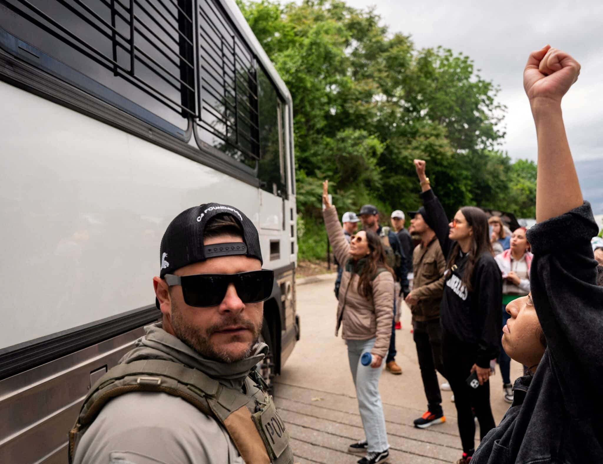 An Immigration and Customs Enforcement officer looks on as a bus transporting detained people leaves the Department of Homeland Security field office in Nashville, where multiple immigrant rights groups gathered to protest what they believe to be a multi-agency operation to detain-noncitizens overnight in Nashville, Tenn., May 4, 2025. (OSV News photo/Seth Herald, Reuters)