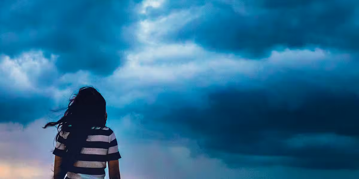 woman facing dark, stormy clouds.
