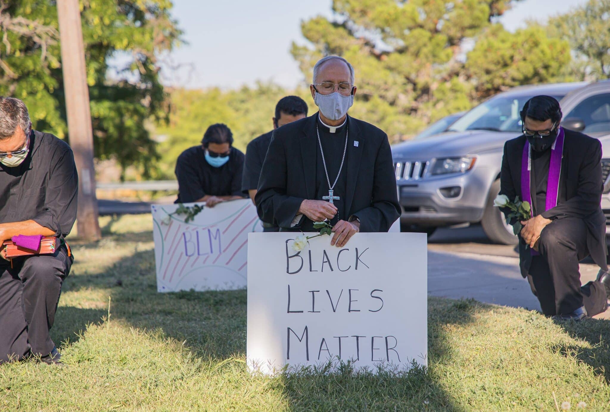 Bishop Mark J. Seitz of El Paso, Texas, kneels at El Paso's Memorial Park holding a "Black Lives Matter" sign June 1, 2020.