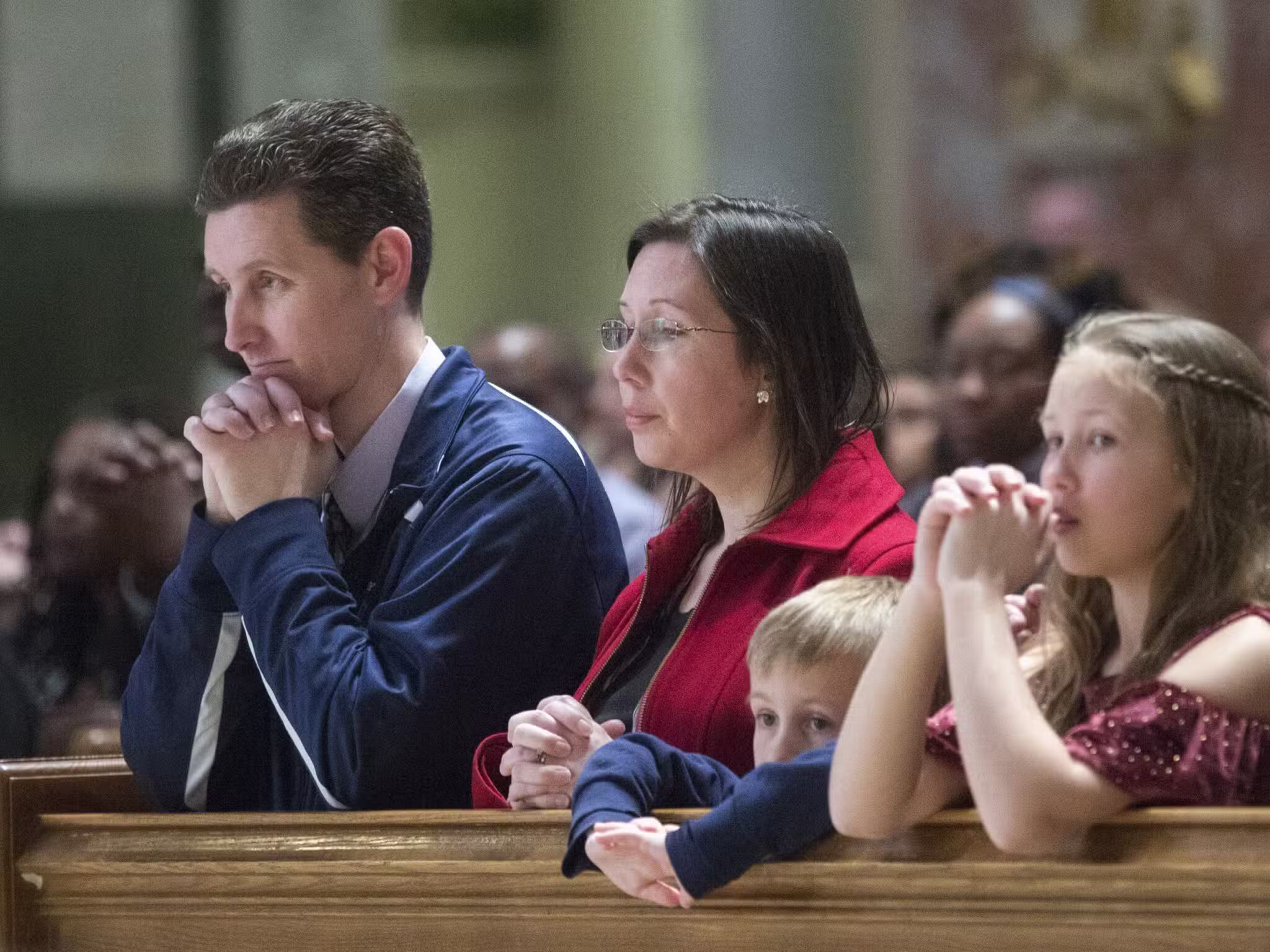A file photo shows a family praying during Mass at the Cathedral of St. Matthew the Apostle in Washington.