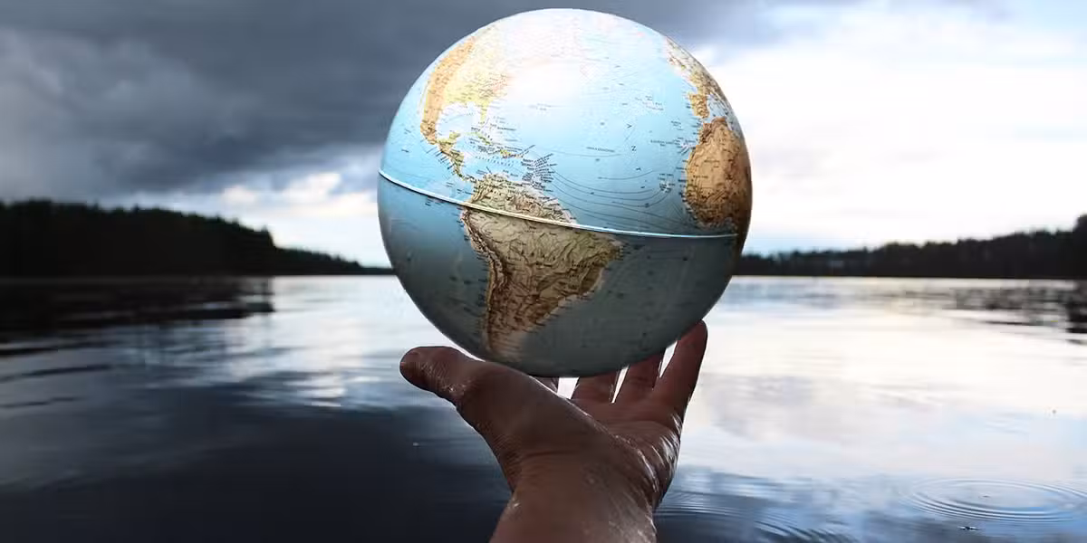 hand holding globe surrounded by nature