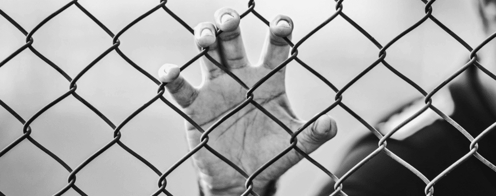 Hand grips a chain-link fence 