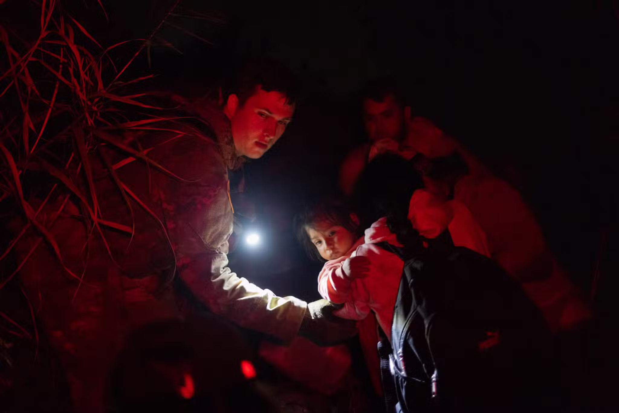 A member of the Texas Army National Guard assists migrants, including Amaiia, a then-1-year-old asylum seeker from Nicaragua, as she and her mother Angelita navigate trails in the dark after crossing the Rio Grande into Roma, Texas, May 8, 2022. Many Nicaraguans continue fleeing their country because of political instability. (OSV News photo/Adrees Latif, Reuters)