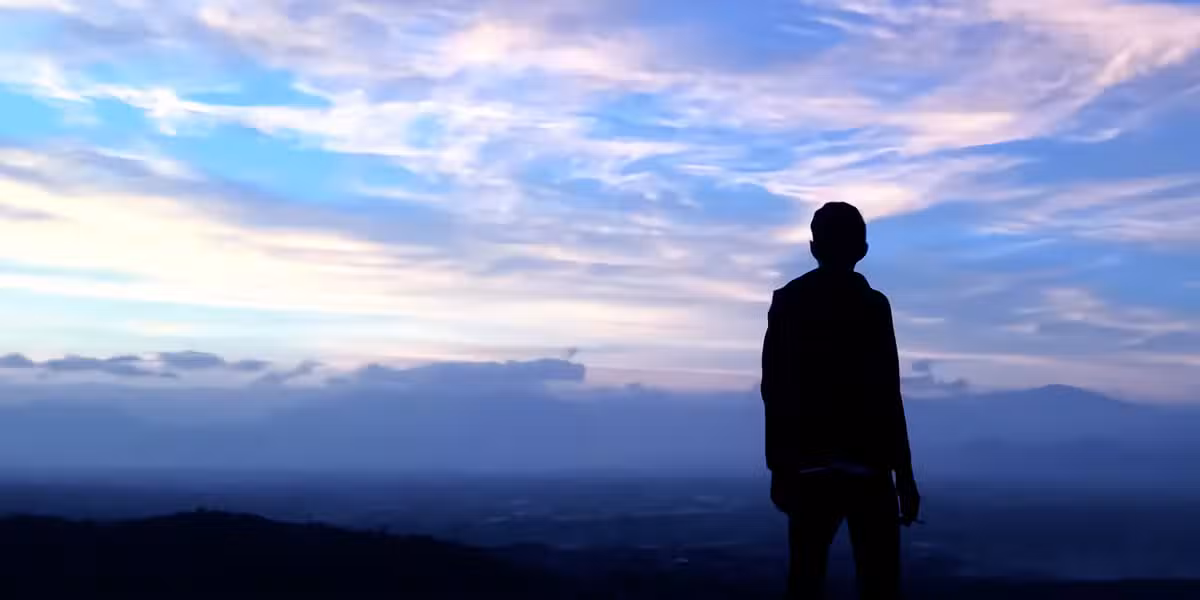silhouette of a man looking up into the cloudy sky