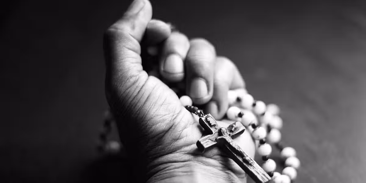 hand holding a rosary with a cross.