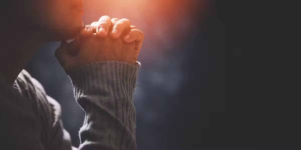 hands folded in prayer with light from behind.