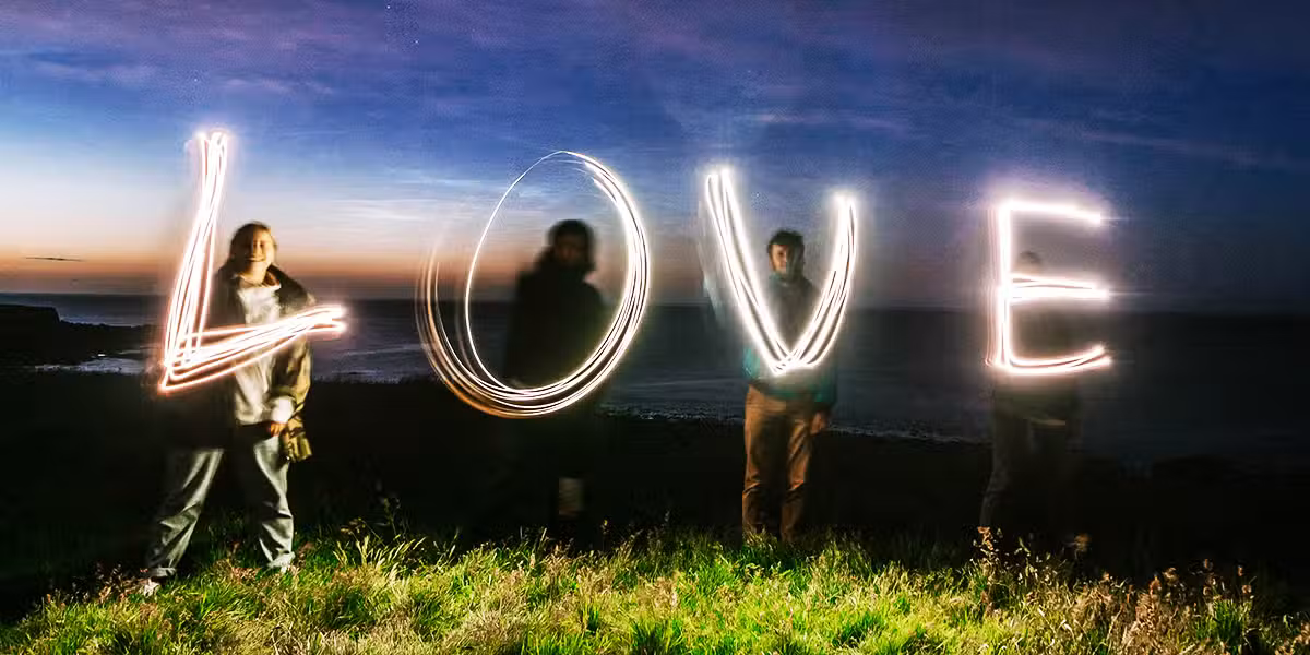 People writing the word "Love" with flash lights into the sky.