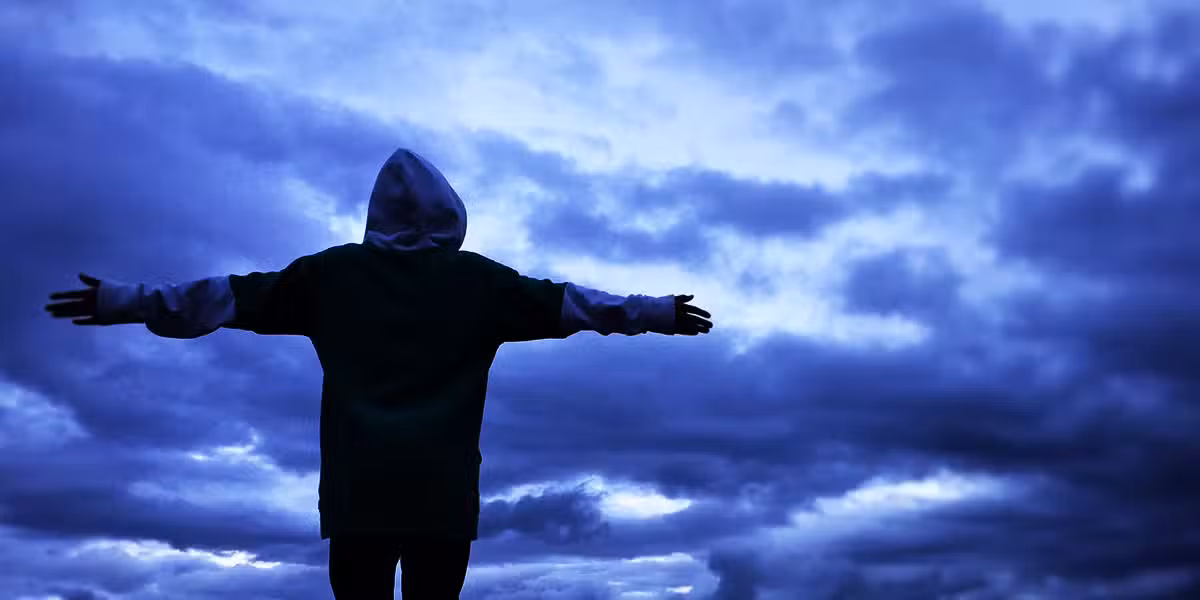 person standing in front of a storm, surrounded by dark clouds.