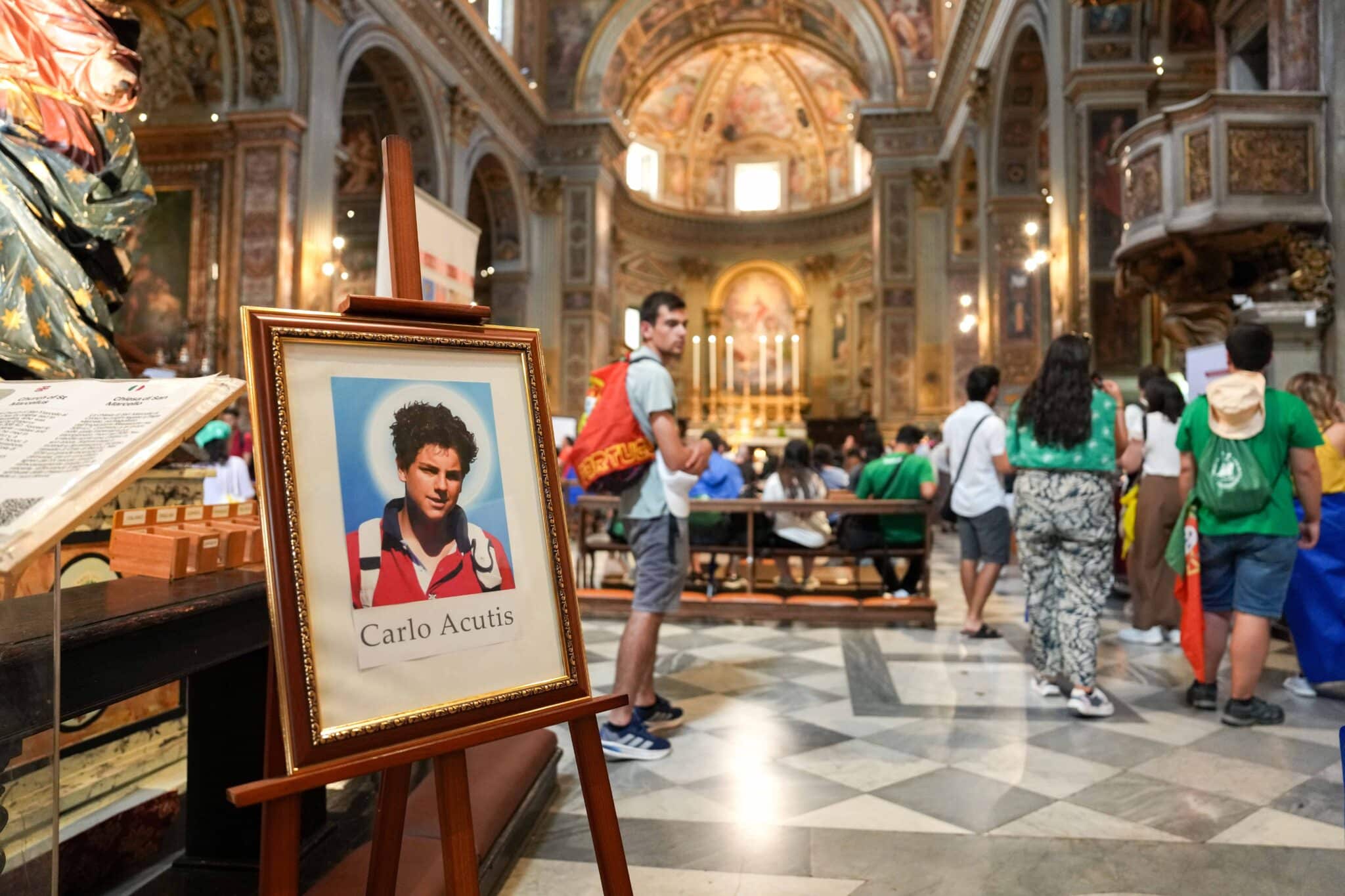 Pilgrims gather near a portrait of Blessed Carlo Acutis at the Church of San Marcello al Corso in Rome, where his relics are displayed July 31, 2025, during the Jubilee of Youth, ahead of his Sept. 7 canonization. (CNS photo/Lola Gomez)