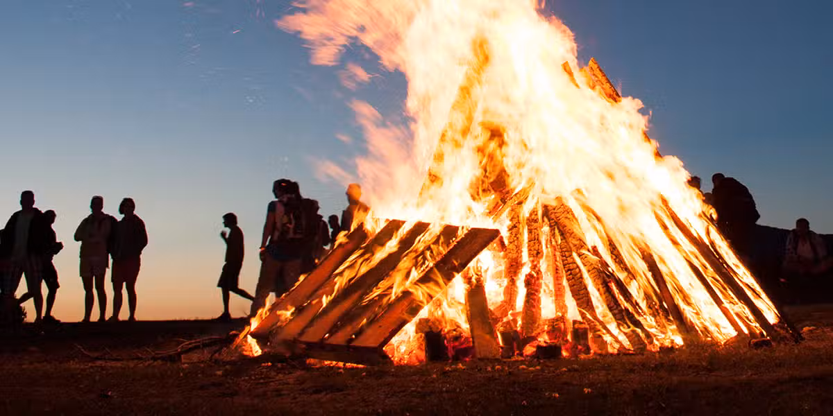 people standing around a large bonfire with clear sky