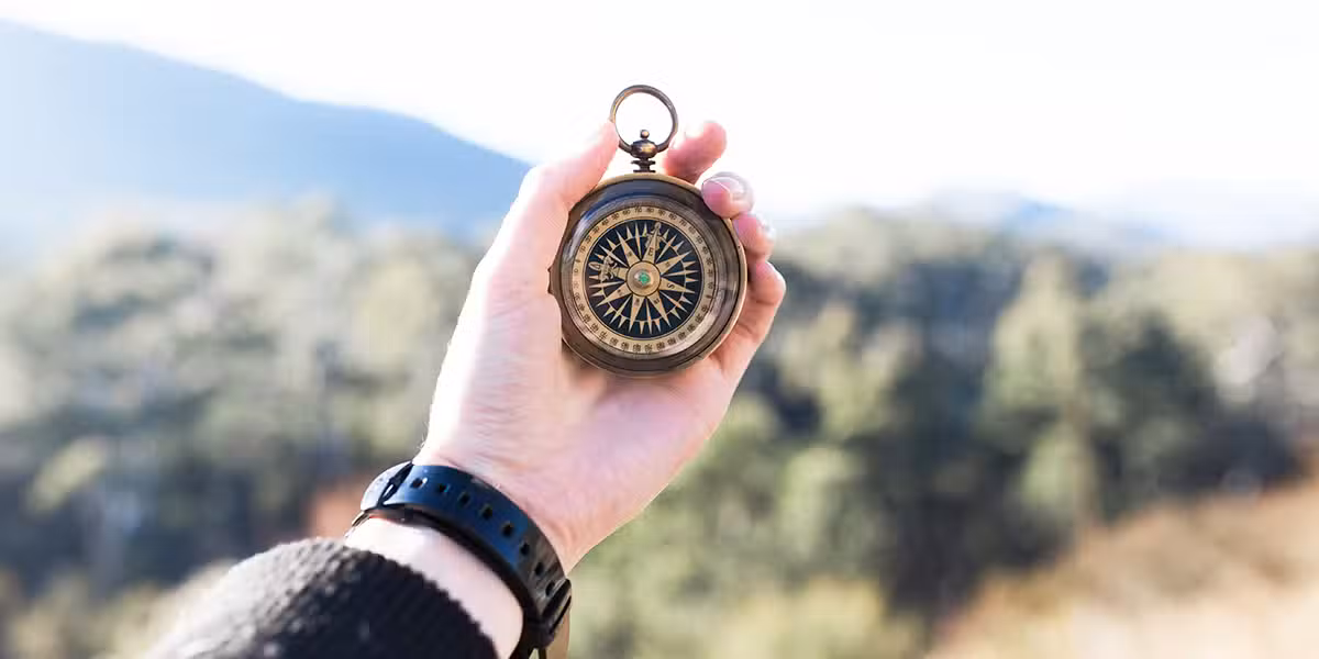 hand holding a compass while on a journey