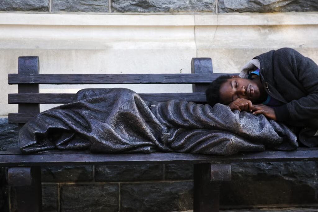 Man rests by a statue of jesus