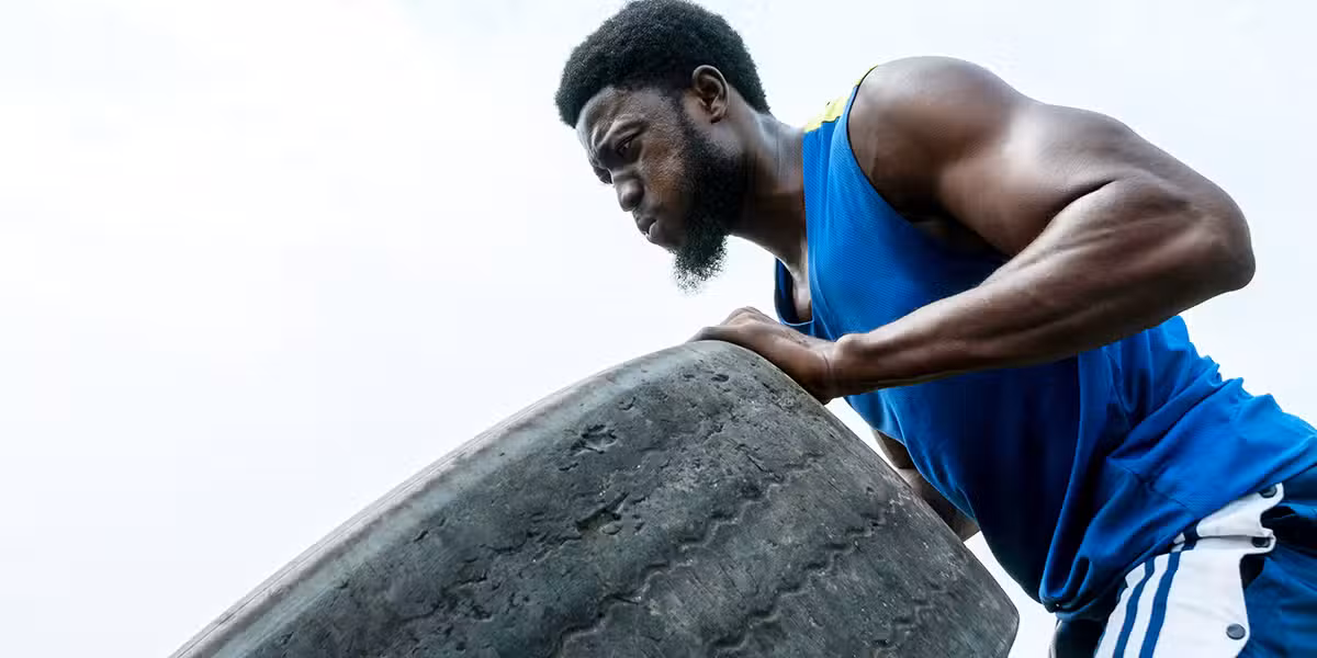 man rolling a heavy tire