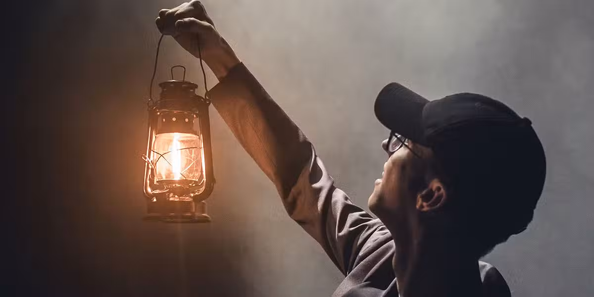 man holding a lantern, lighting up the room