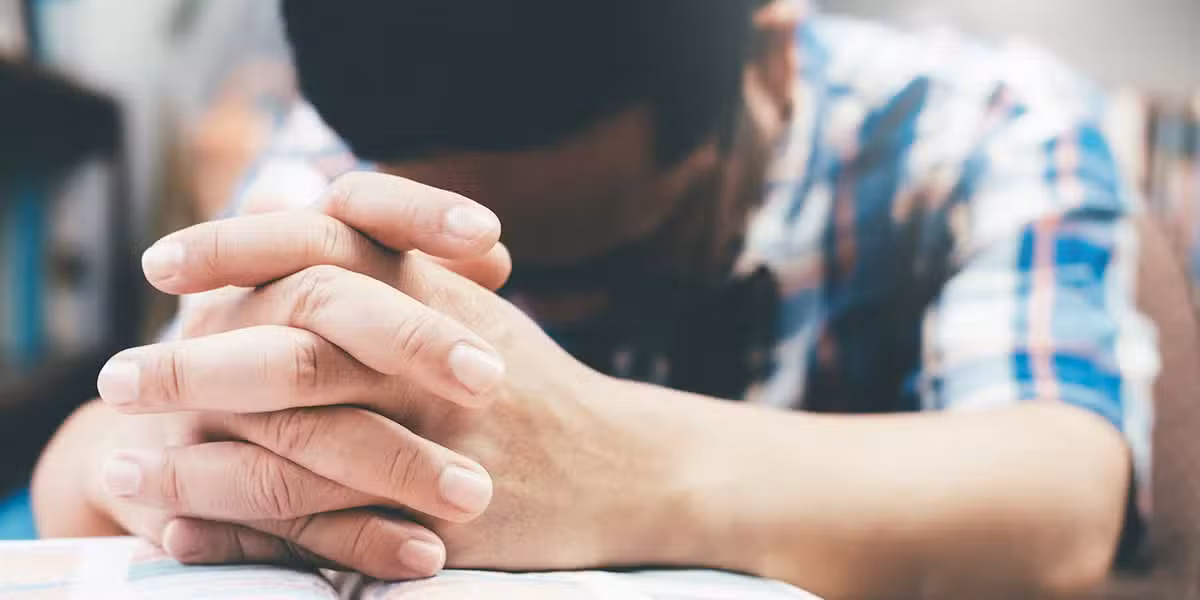 Man praying with hands folded.