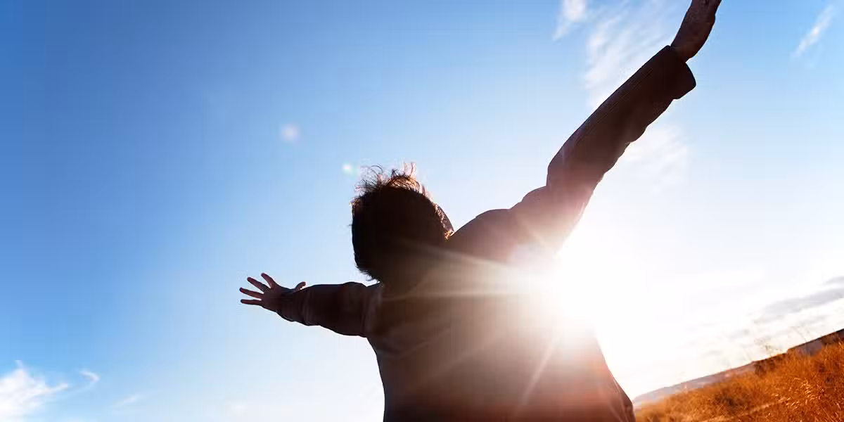 person looking into the sky and surrendering with open arms