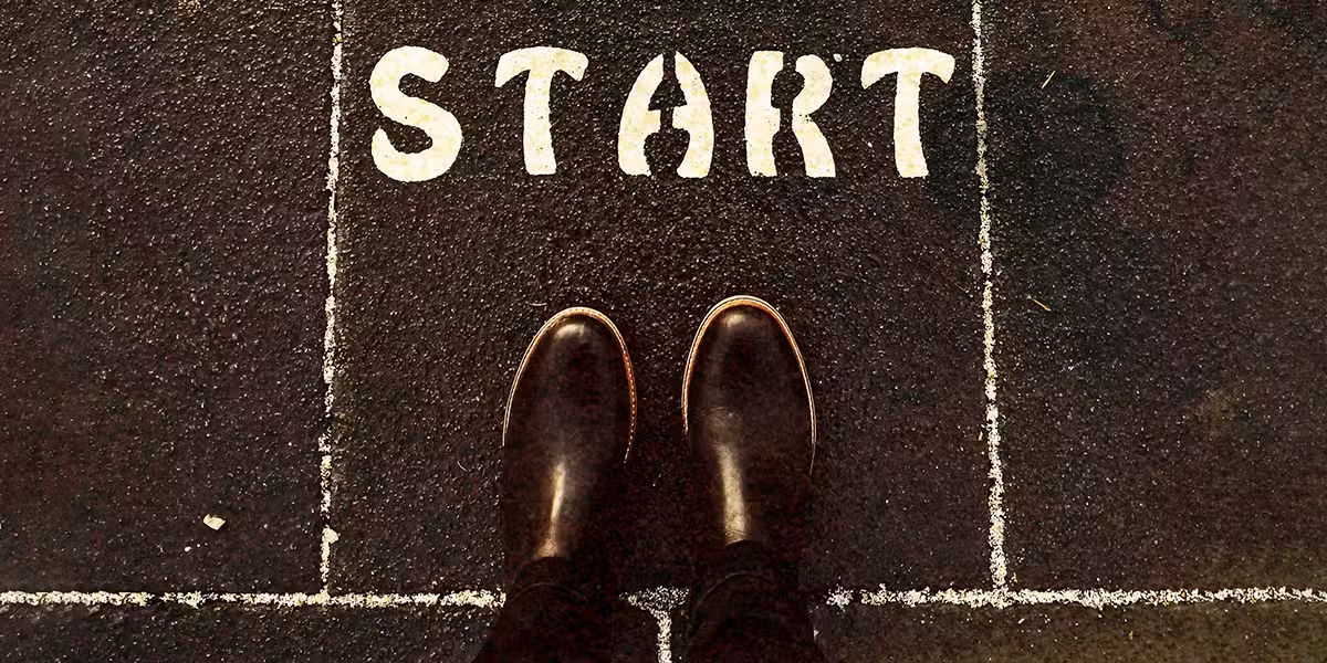 shoes and feet lined up on a line with the word start written on pavement