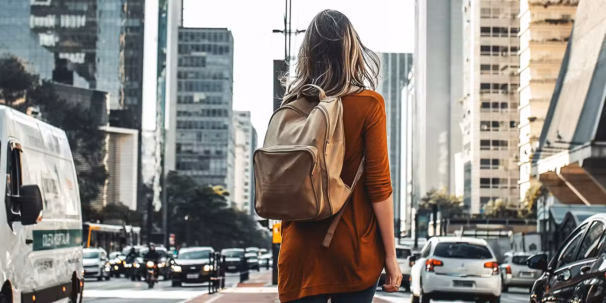 woman walking in a city carrying a backpack