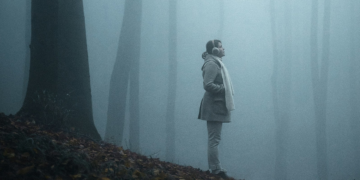 woman standing in a forest during fog.