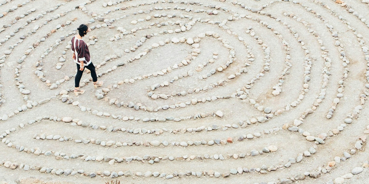 woman walking through a maze made out of stones.