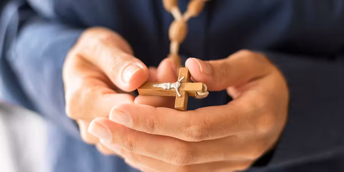 hands holding a cross necklace