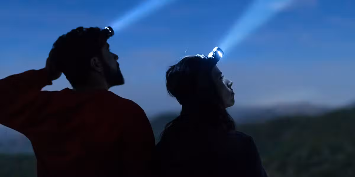 couple people with head lights shining into the darkness