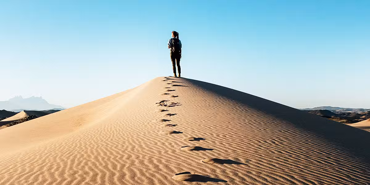 person ahead, following the footsteps in the sand