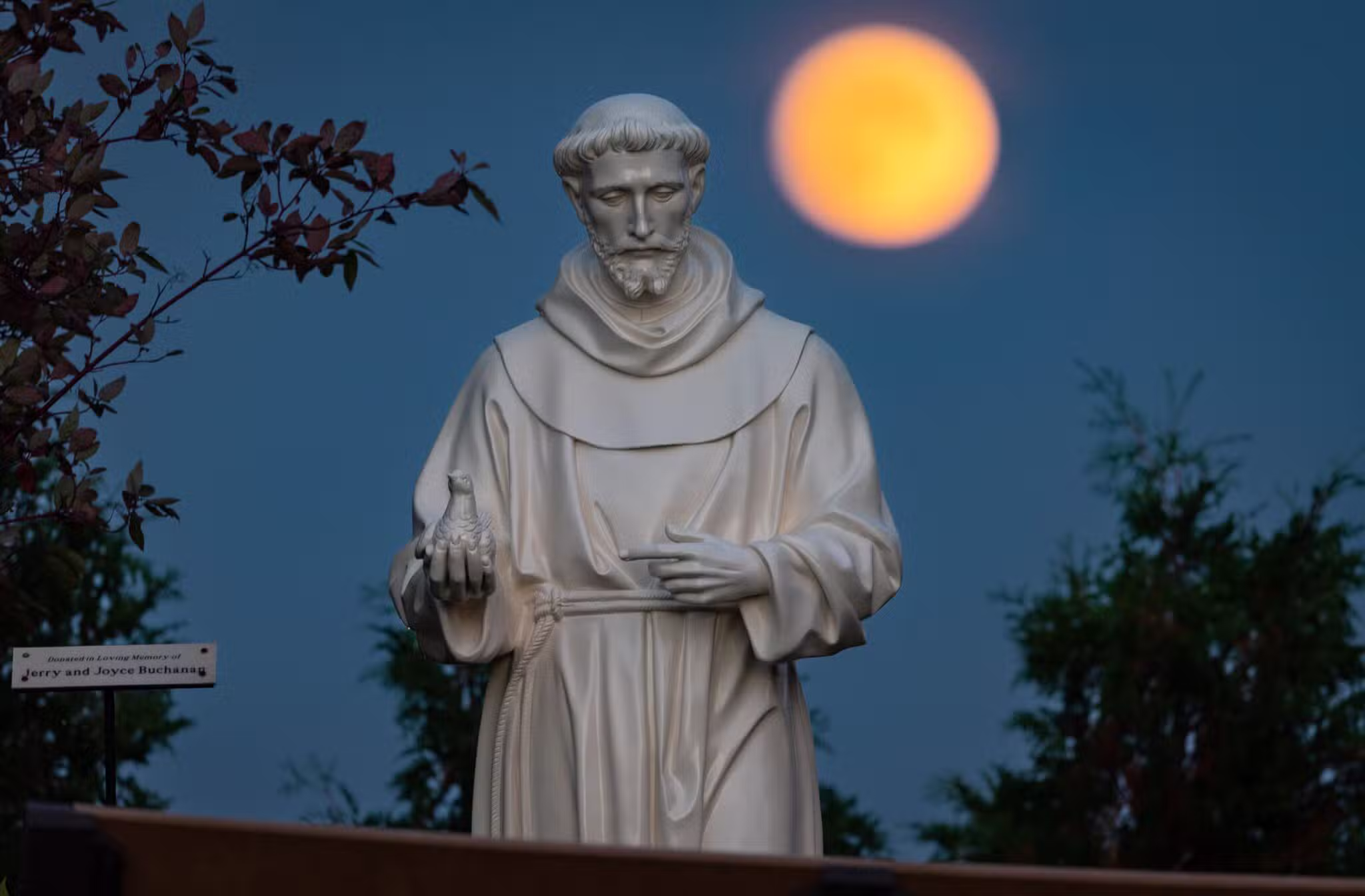 A hunter's moon rises behind a statue of St. Francis of Assisi on the grounds of the National Shrine of Our Lady of Champion in Champion, Wisconsin.