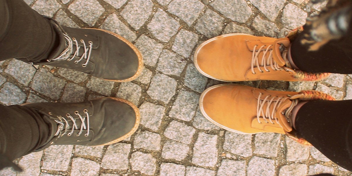 two people showing their legs and shoes standing across from each other in conversation.