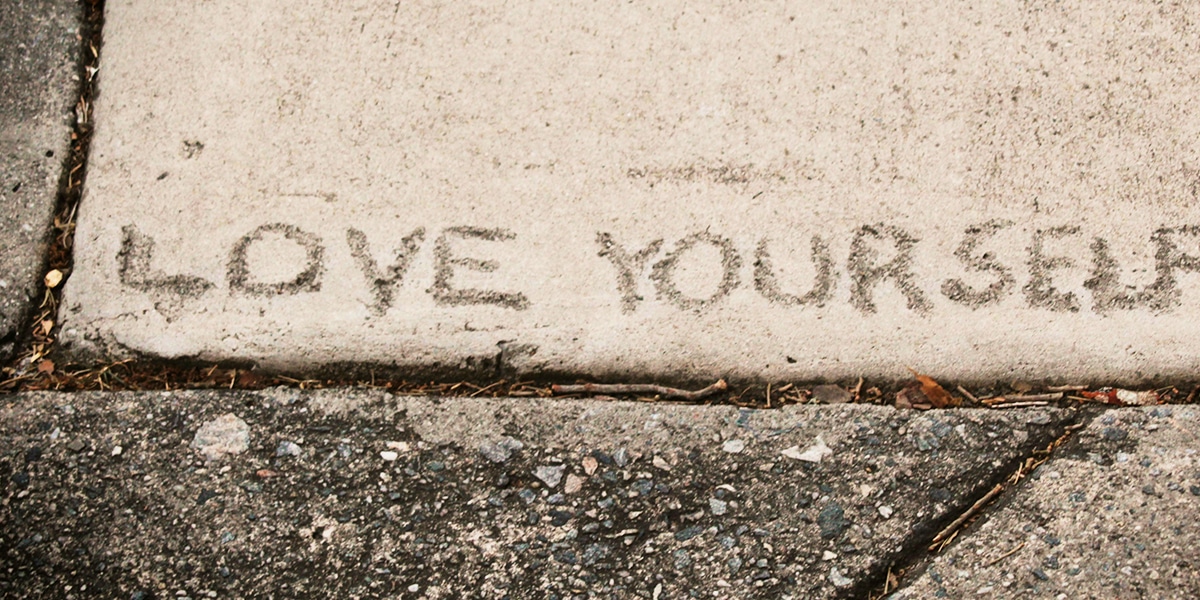 The words "Love Yourself" scratched into the pavement.